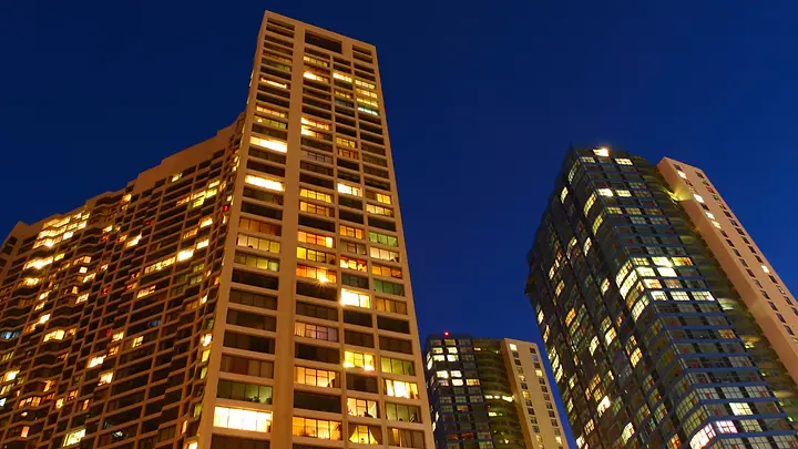 Prédios residenciais com as janelas acesas à noite, vistos de baixo
